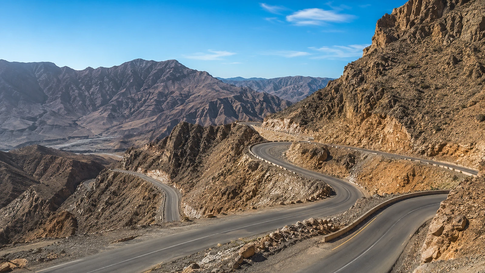 Private tour van on a Ras Al Khaimah mountain road with Jebel Jais scenery and a group of travellers.